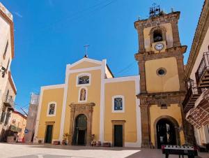 a church with a clock tower in a street at Sofi House in Santo Stefano di Camastra