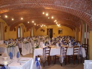 un salón de banquetes con mesas y sillas blancas en Agriturismo La Desiderata, en Agliè