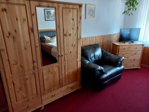 a room with a leather chair and a bedroom at Pension Zur Elbe in Lutherstadt Wittenberg