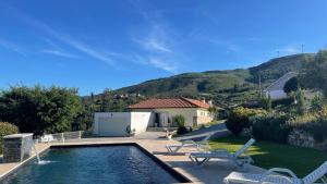 una piscina con dos sillas y una casa en Quinta D'Arroteia, en Monção