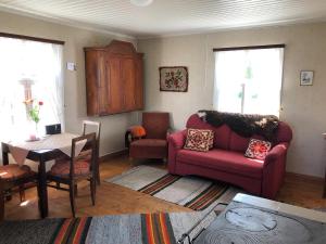 a living room with a red couch and a table at Abbis lillstuga in Norra Vallgrund