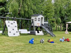 a playground with a slide and toys in the grass at Dom Wypoczynkowy LAGUNA Gąski in Gąski