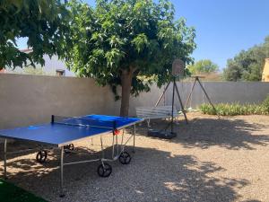 una mesa de ping pong y un banco frente a un árbol en Gîte domaine de la source bas en Vias