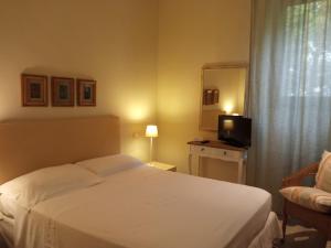 una camera d'albergo con letto bianco e TV di Hotel Touring a Livorno