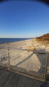 a fence on a beach with the ocean in the background at Apartament Hexagon nr 36 in Grzybowo