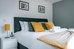 a bedroom with a large white bed with yellow pillows at St Albans City Centre Apartment in St. Albans