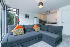 a living room with a blue couch with pillows at St Albans City Centre Apartment in Saint Albans