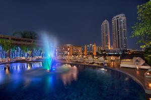 a pool with a fountain in a city at night at Riva Surya Bangkok - SHA Extra Plus in Bangkok