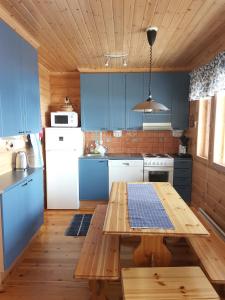 クーサモにあるSininen Hetki Cottageのキッチン(青いキャビネット、木製テーブル付)