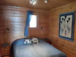 a bedroom with a bed in a log cabin at Sininen Hetki Cottage in Kuusamo