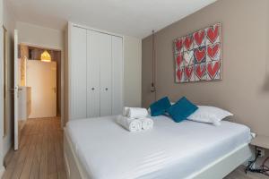 a bedroom with a white bed with blue pillows at SIROCCO - Bel appartement avec extérieur proche des plages in Marseille