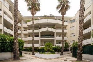 an apartment building with palm trees in front of it at SIROCCO - Bel appartement avec extérieur proche des plages in Marseille