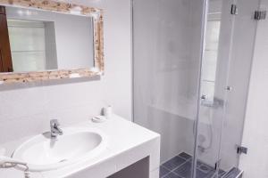 a white bathroom with a sink and a shower at Porto Elea Camping & Bungalows in Metókhion Zográfou