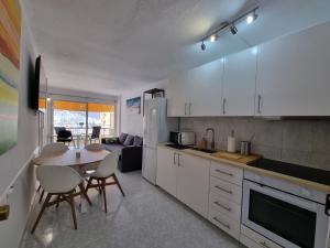 a kitchen with white cabinets and a table with chairs at Torres del Sol 12th floor Teide and Atlantic view - Las Americas in Playa de las Americas