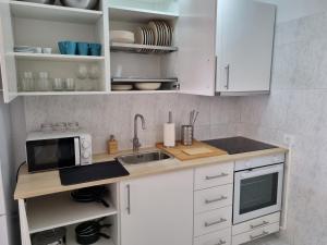 a kitchen with white cabinets and a sink and a microwave at Torres del Sol 12th floor Teide and Atlantic view - Las Americas in Playa de las Americas