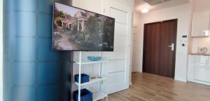 a tv hanging on a blue wall in a room at Aleda Hanza 14 floor, balkon in Szczecin