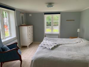 a bedroom with a bed and a dresser and two windows at Holiday home Tussered Hacksvik in Håcksvik