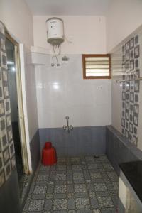 a bathroom with a red bucket on the floor at Ranga Residency in Mayiladuthurai