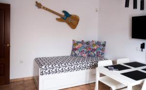a white couch with a guitar hanging on a wall at Villa Elisa in Villaverde