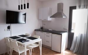 een keuken met een witte tafel, witte kasten en een fornuis bij Villa Elisa in Villaverde