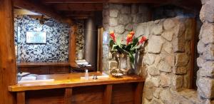 a room with a stone wall with a table with flowers at Dos Bahias Lake Resort in Villa La Angostura