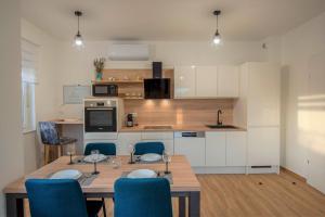 a kitchen with a wooden table and blue chairs at My Adriatic Suite with private garden in Šibenik