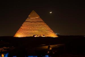 uma imagem das pirâmides à noite com a lua em Marvel Stone Hotel no Cairo
