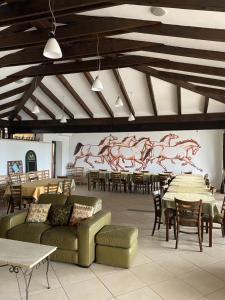 een grote ruimte met tafels en banken en een muurschildering van paarden bij Country Club La Mesteceni in Sebeş