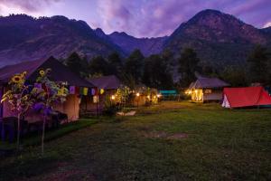 un grupo de tiendas de campaña en un campo por la noche en Odyssey Stays Parvati Woods Camps, en Kasol