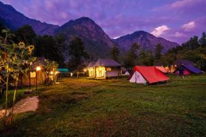 un grupo de tiendas de campaña en un campo con montañas en Odyssey Stays Parvati Woods Camps, en Kasol