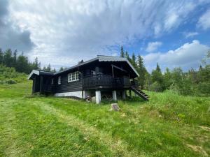Ein schwarzes Haus auf einem Hügel auf einem Feld in der Unterkunft Lifjelltunet in Lifjell