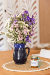 niebieska waza z fioletowo-białymi kwiatami i słoik miodu w obiekcie AGIAZI Poros Summer House w mieście Galatas
