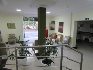 eine Lobby mit Stühlen und einem Tisch mit Pflanzen in der Unterkunft Hotel Monteneve in São Paulo
