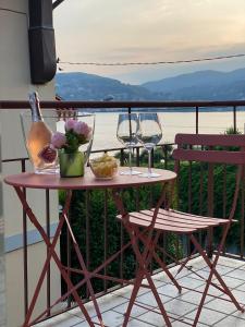 a table with two wine glasses and flowers on a balcony at Bnbook La Casa di Orazio & Carla in Ranco