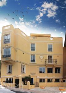 żółty budynek z ptakami latającymi po niebie w obiekcie CHARMANT STUDIO RENOVÉ 150m DE MONACO w mieście Beausoleil