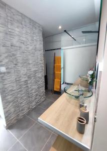 ein Badezimmer mit einem Glastisch und einer Steinmauer in der Unterkunft Grey Diamond Studio in Le Diamant