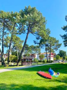 a person sitting on the grass next to a red surfboard at HOSSEGOR Plage & Golf in Hossegor