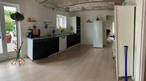 a kitchen with a white refrigerator and a wooden floor at Under Regnbuen, dit fristed på Hærvejen in Them