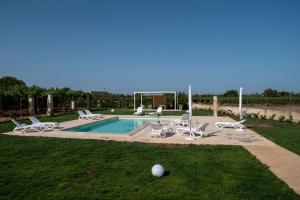 uma piscina com espreguiçadeiras e uma bola na relva em IL NOCE Salento Tourism Services em Nardò