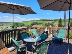 eine Terrasse mit Stühlen, einem Tisch und einem Sonnenschirm in der Unterkunft Ferienwohnung Geiernest in Ochsenfurt