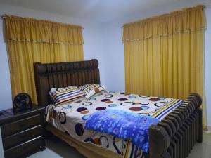 a bed in a bedroom with yellow curtains at Caribean Dreams Apartement Beautiful Pool and Gym in Santiago de los Caballeros +14 photos