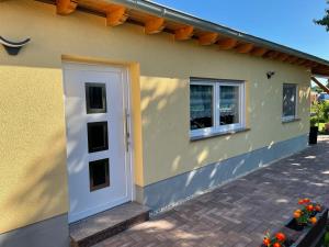 una casa amarilla con una puerta blanca y una ventana en Ferienwohnung Arthur, en Luckenwalde