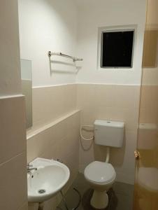 a bathroom with a toilet and a sink and a window at CH Budget Hotel in Cameron Highlands