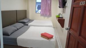 2 camas en una habitación pequeña con una toalla roja en CH Budget Hotel en Cameron Highlands