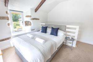 a white bedroom with a large bed with blue pillows at Cosy 1 bedroom Cottage - Great location & Parking in Penzance