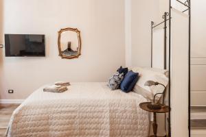 a white bedroom with a bed and a mirror at La conchiglia in Lucca
