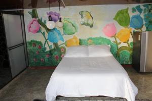 una camera da letto con un letto bianco e un dipinto sul muro di el paraíso de Butulú 1 a La Vega