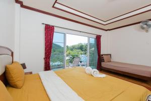 a bedroom with a large bed and a window at Patong Rai Rum Yen Resort SHA in Patong Beach