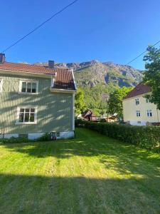 a house with a green yard with a mountain in the background at Sentral tomannsbolig ved park, Rjukan in Rjukan