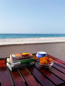 a picnic table with books and oranges on the beach at Pansion Giannis Perris in Kokkari